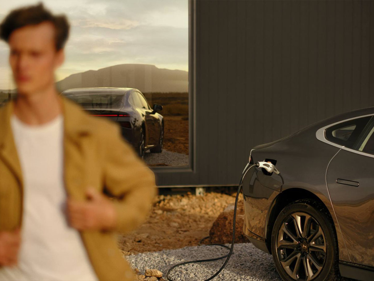 A man stands with his XPENG vehicle while it charges.